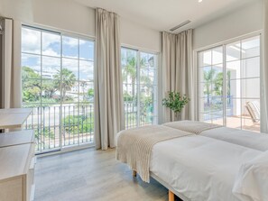 Ein Schlafzimmer mit großem Fenster, einem Bett, einem Nachttisch und Blick ins Freie.