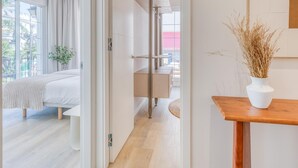 A modern hotel room with a bed, a wooden nightstand, a vase with dried plants, and a view of the outside. - Modern apartment near the port - 4 guests (Estepona)