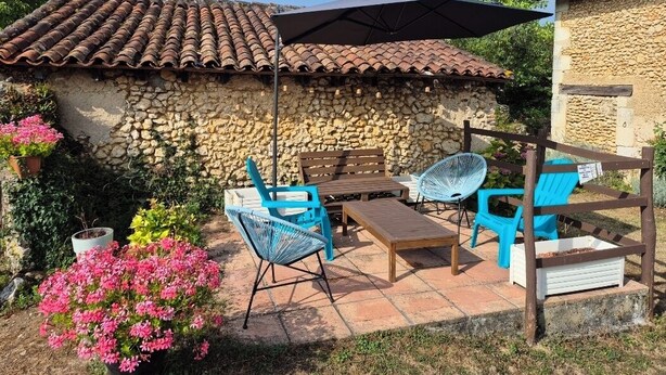 Une terrasse avec des murs en pierre, un toit en tuiles et du mobilier d’extérieur.