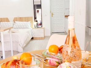 A hotel room with a bed, bedside table, a dining table with food and drinks, and a door. - Modern studio 50m from the beach with air conditioning (Los Cristianos)