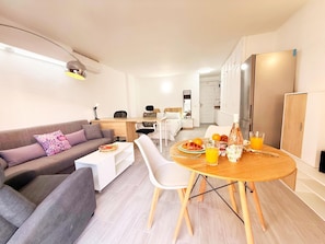 A modern living room with a sofa, a dining table with chairs, a kitchen area, and a bedroom with a bed and nightstand. - Modern studio 50m from the beach with air conditioning (Los Cristianos)
