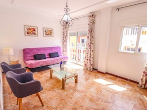 A living room with a pink sofa, two armchairs, a glass coffee table, and a chandelier. - Apartment in Playa San Juan, near beach, wifi, parking (Playa San Juan)