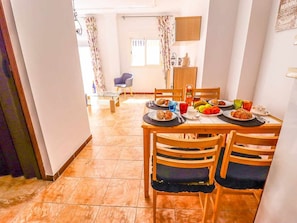 A dining area with a table set for breakfast, chairs, a chair in the background, and a window with curtains. - Apartment in Playa San Juan, near beach, wifi, parking (Playa San Juan)
