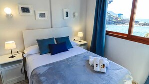 Une chambre d’hôtel avec un lit, deux tables de chevet, une fenêtre avec des rideaux et des tableaux encadrés au mur.