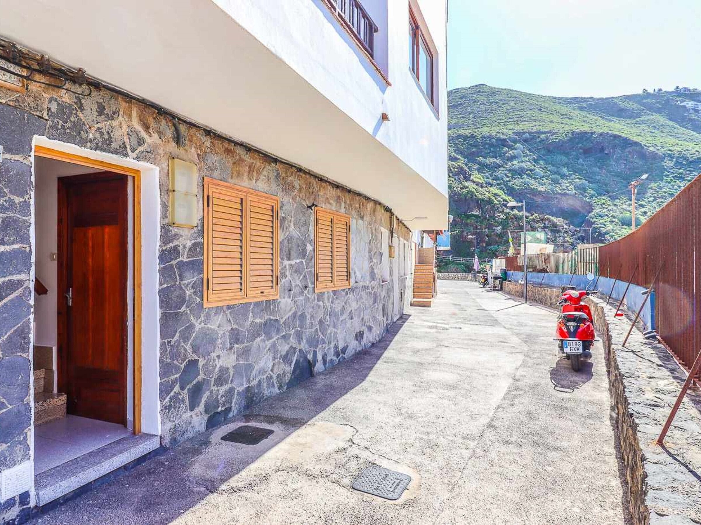 Ein Gebäude mit einer steinernen Fassade, hölzernen Fensterläden und freiem Blick auf eine hügelige Landschaft.