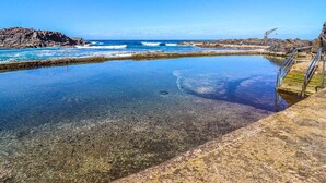 Une piscine aux eaux limpides, avec des marches menant à une rive rocheuse.
