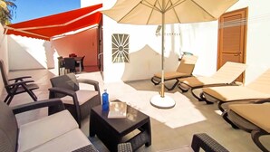 Un patio con sillones de descanso, una mesa y una sombrilla grande.