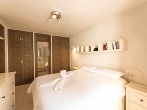 Ein Hotelzimmer mit Bett, Nachttischen, einem Kleiderschrank und einem Bücherregal.