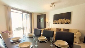 Un comedor con una mesa dispuesta para cuatro personas, un sofá y una obra de arte con temática de cebra en la pared.