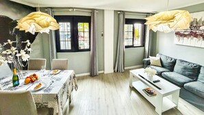 A modern living room with a dining area, featuring a table set with food, a sofa, and a coffee table. - Beautifully decorated apartment in Adeje, close to beach (Adeje)