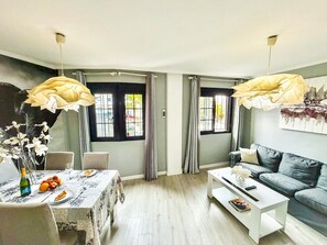 A modern living room with a dining area, featuring a table set with food, a sofa, and a coffee table. - Beautifully decorated apartment in Adeje, close to beach (Adeje)