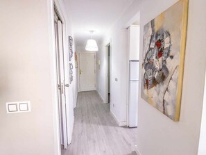 A hallway with a white door, a white refrigerator, and a pendant light. - Beautifully decorated apartment in Adeje, close to beach (Adeje)
