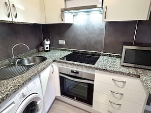 A compact kitchen with a stainless steel sink, a built-in microwave, a stovetop, and a dishwasher. - Beautifully decorated apartment in Adeje, close to beach (Adeje)