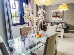 A dining area with a glass table, chairs, and a vase with flowers. - Beautifully decorated apartment in Adeje, close to beach (Adeje)