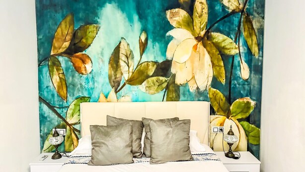 A bedroom with a bed, pillows, a nightstand, a lamp, and a wall tapestry. - Beautifully decorated apartment in Adeje, close to beach (Adeje)