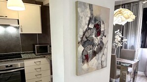 A modern kitchen with a microwave, oven, and cabinets. There is a dining area with a table and chairs. - Beautifully decorated apartment in Adeje, close to beach (Adeje)