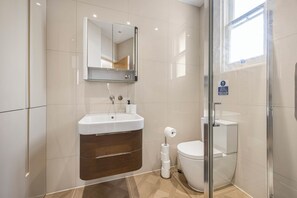 Een moderne badkamer met een glazen douchecabine, een ingebouwd wastafelmeubel met spiegel en een toilet.