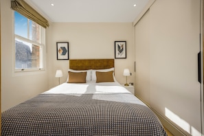 Hotelkamer met een groot bed, twee nachtkastjes, een raam met gordijnen en lijstwerken aan de wanden.