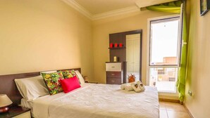 Un dormitorio con cama, mesita de noche, cómoda y vistas al exterior.