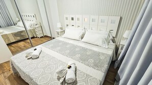 Una camera d'albergo con un letto grande, un comodino, uno specchio e una finestra con tende.