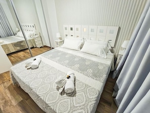 A hotel room with a large bed, a bedside table, a mirror, and a window with curtains. - Bright apartment with sea view - 2 guests (Costa Adeje)