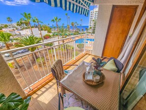 A balcony with a view of palm trees and a building across the street. - Bright apartment with sea view - 2 guests (Costa Adeje)