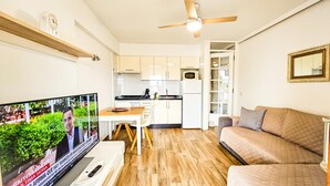 Un soggiorno moderno con televisione, un divano, un tavolo da pranzo e una zona cucina.