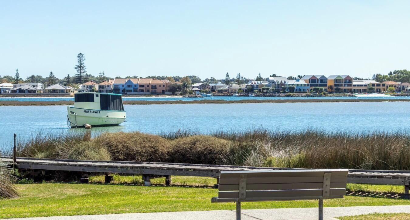 A waterfront view with a boat named 'Mayflower' and a bench in the foreground.