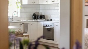 A kitchen with white cabinets, a toaster, a kettle, and an oven. - The Art Lovers Cottage in Mandurah 1BR (Dudley Park)