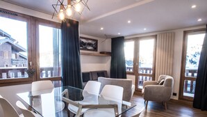 Ein modernes Zimmer mit einem Glastisch, umgeben von Stühlen, einer Couch und einem Kamin.