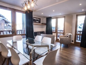 Ein modernes Zimmer mit einem Glastisch, umgeben von Stühlen, einer Couch und einem Kamin.
