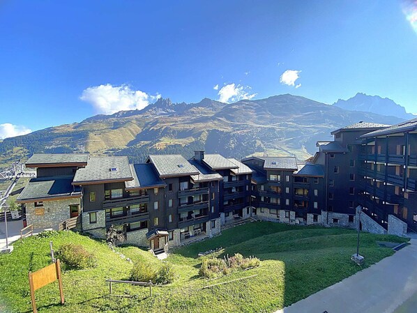Ein Bergresort mit mehrstöckigen Gebäuden, einem grasbewachsen Innenhof und Blick auf schneebedeckte Berge.
