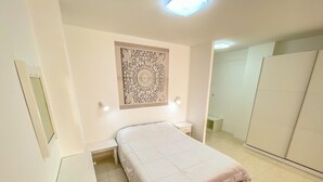 Quarto com cama, escrivaninha, cadeira, guarda-roupa e um detalhe decorativo na parede.