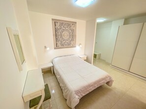 A bedroom with a bed, a desk, a chair, a wardrobe, and a decorative wall piece. - Spacious studio 100m from beach, ideal for couples (Los Cristianos)