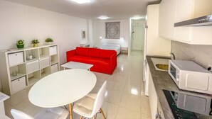 Um espaço de estar moderno e compacto, com cozinha compacta, área de refeições e sofá vermelho.