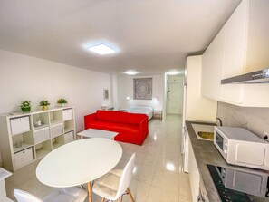 A modern, compact living space with a kitchenette, a dining area, and a red sofa. - Spacious studio 100m from beach, ideal for couples (Los Cristianos)
