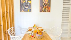 A dining area with a wooden table, white chairs, and artwork on the wall. - Luxury studio, sea view in Tenerife (Playa Paraiso)