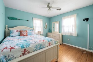 A bedroom with a bed, dresser, nightstand, and a ceiling fan.