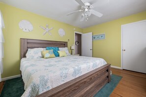 A bedroom with a bed, a ceiling fan, and a door.