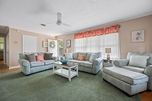 A living room with two sofas, a coffee table, and a window with blinds.