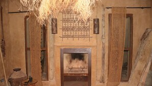 Una habitación rústica con chimenea, un tapiz tejido y una silla tradicional de fibra.