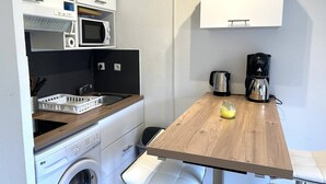 En lille tekøkken med mikroovn, kaffemaskine, elkedel og vask.