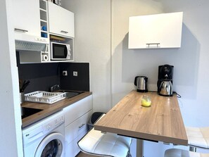 Eine kleine Küchenzeile mit Mikrowelle, Kaffeemaschine, Wasserkocher und Spüle.