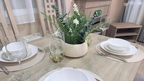 A dining table set with plates, glasses, and cutlery, a potted plant, and a small table with a glass. - Fantasy Island H12 Caravan With Hot Tub (Skegness)