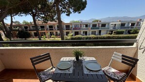 A balcony with a table set for two, chairs, and a potted plant. - Renovated studio, terrace - 2 guests (Argelès-sur-Mer)