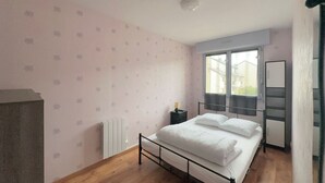 Ein Schlafzimmer mit Bett, Heizkörper, Fenster und Tür.