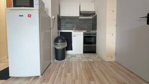 Eine kleine Küche mit Kühlschrank, Backofen und Mikrowelle.