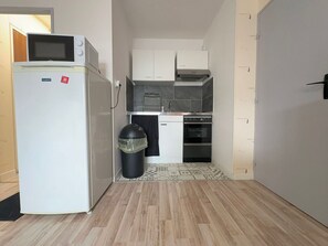 A compact kitchen with a refrigerator, oven, and microwave. - Cozy apartment near the sea - 4 guests (Courseulles-sur-Mer)