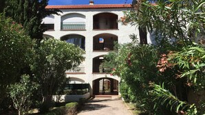 Un edificio a più piani con un cortile centrale, circondato da vegetazione lussureggiante e alberi.