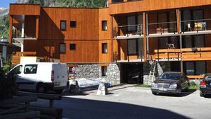 A modern multi-story building with wooden exterior walls, a stone base, and balconies. - Bright studio for 2 in Val d'Isère (Val-d'Isère)